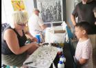 Julie Landrum demonstrates how to create marble designs on paper using shaving cream and food coloring at the Sip and strut event held in Downtown Lampasas Thursday evening.