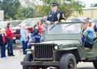 CCLP/LYNETTE SOWELL - World War II veteran and Pearl Harbor survivor Ret. 1SGT Henri “Hank” Grenier stands in a military jeep as he makes his way through the parade route, Friday.
