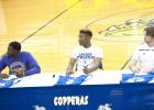 CCLP/DAVID MORRIS - Copperas Cove football players from left: Quarterback Caine Garner (Division III University of Mary-Hardin Baylor), running back Elijah Washington (Div. III Howard Payne University) and deep snapper Sean Adams (Div. I New Mexico State) listen as associate head coach and offensive coordinator Tracy Welch speaks during a signing ceremony Wednesday at the school.