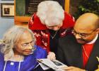 Barbara Burke, one of Alither Mae Stephens’ Golden Girl bowling buddies, looks at a newspaper article along with Stephens and Bishop Nathaniel Holcomb.